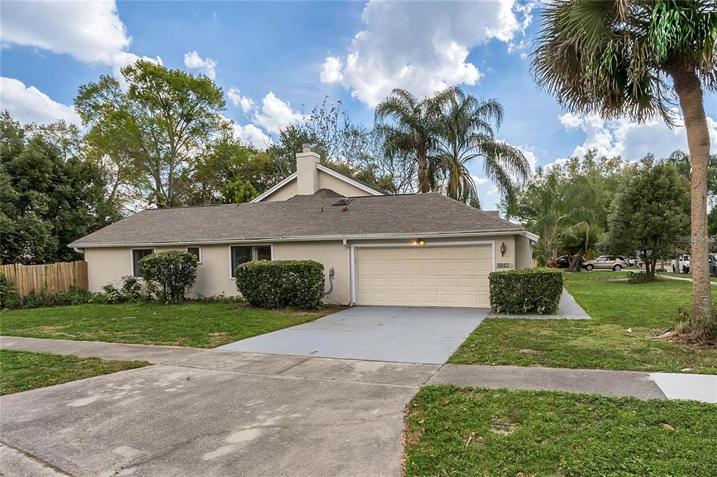 A single-story house with a beige exterior, a two-car garage, and a concrete driveway — 5607 SPRING RUN AVENUE, ORLANDO, FL