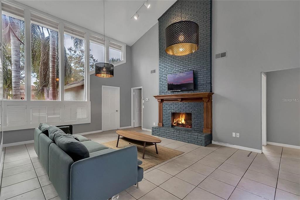 A living room features a tall gray brick fireplace, tile floors, and large windows — 5607 SPRING RUN AVENUE, ORLANDO, FL