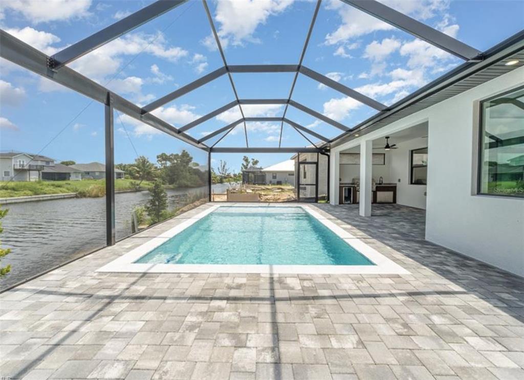A rectangular swimming pool sits on a paved patio enclosed by a screened lanai — 1801 SW 15TH PLACE, CAPE CORAL, FL
