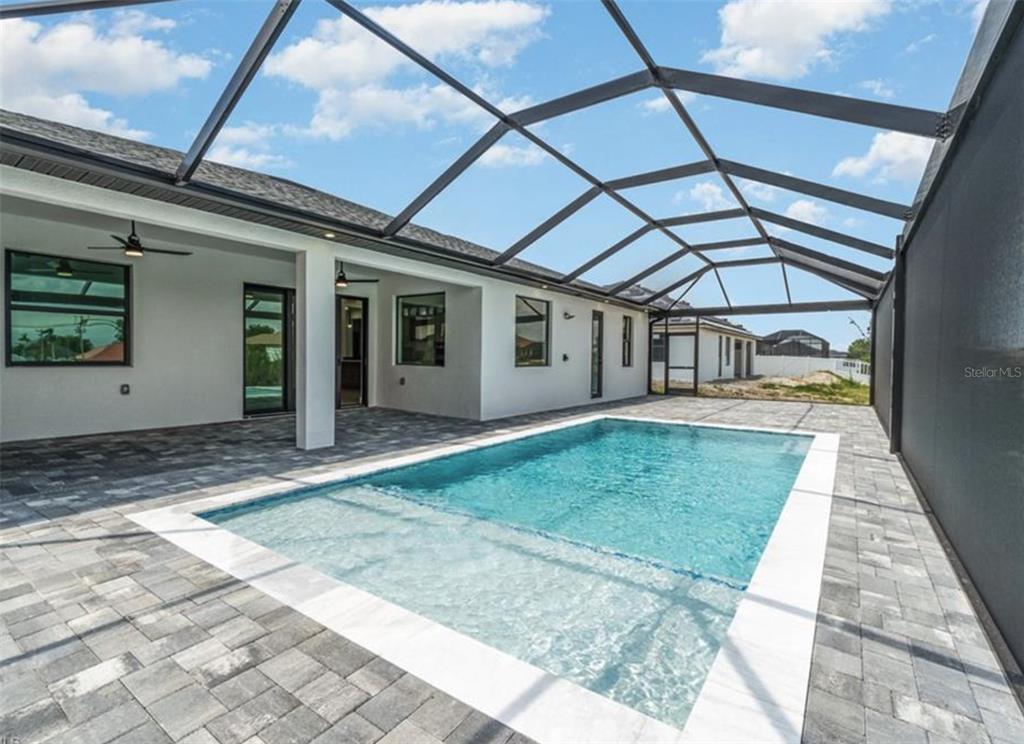 A rectangular swimming pool sits on a paved patio inside a screened-in lanai — 1801 SW 15TH PLACE, CAPE CORAL, FL
