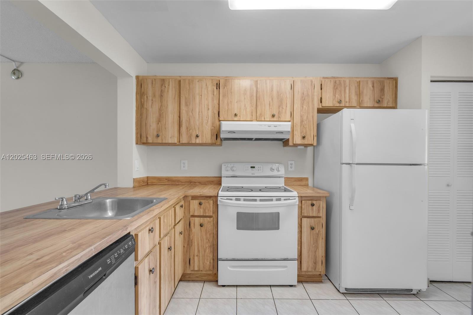 A kitchen features light wood cabinets, white appliances, and a stainless steel sink — 841 NE 207th Ln # 201, Miami FL 33179, MIAMI, FL