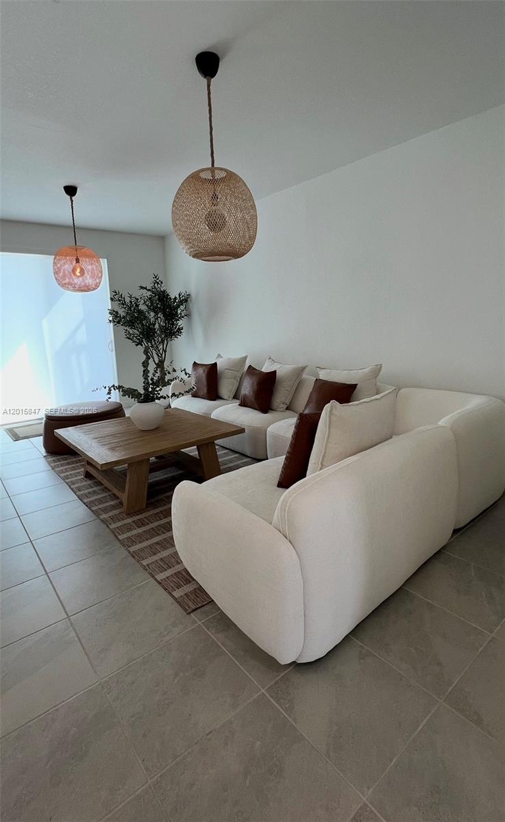 A living room features a white sectional sofa, a wooden coffee table, and two pendant lights — 686 SE 13th Ct, Homestead FL 33034, HOMESTEAD, FL