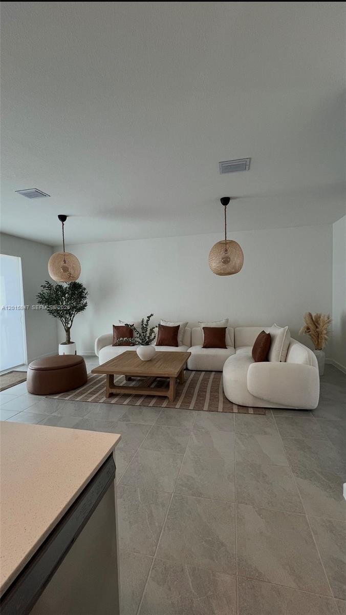 A living room features a white sectional sofa, a wooden coffee table, and two pendant lights — 686 SE 13th Ct, Homestead FL 33034, HOMESTEAD, FL