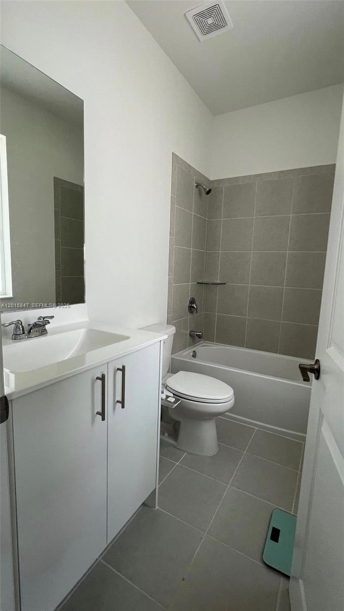 A bathroom features a white vanity, a toilet, and a shower-tub combo with gray tiles — 686 SE 13th Ct, Homestead FL 33034, HOMESTEAD, FL