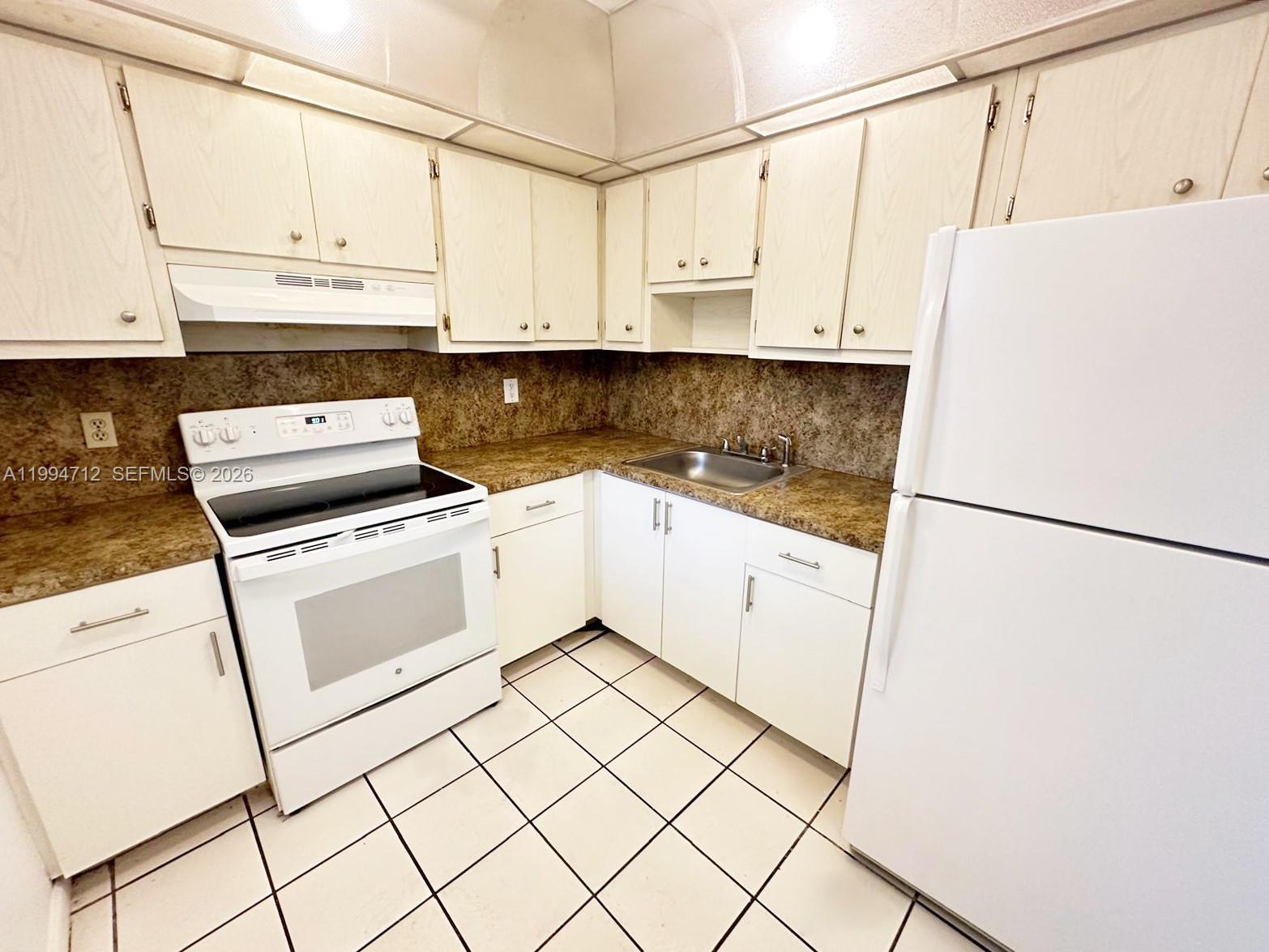 A kitchen features white cabinets, a white stove, a white refrigerator, and brown countertops — 15600 NW 7th Ave # 606, Miami FL 33169, MIAMI, FL