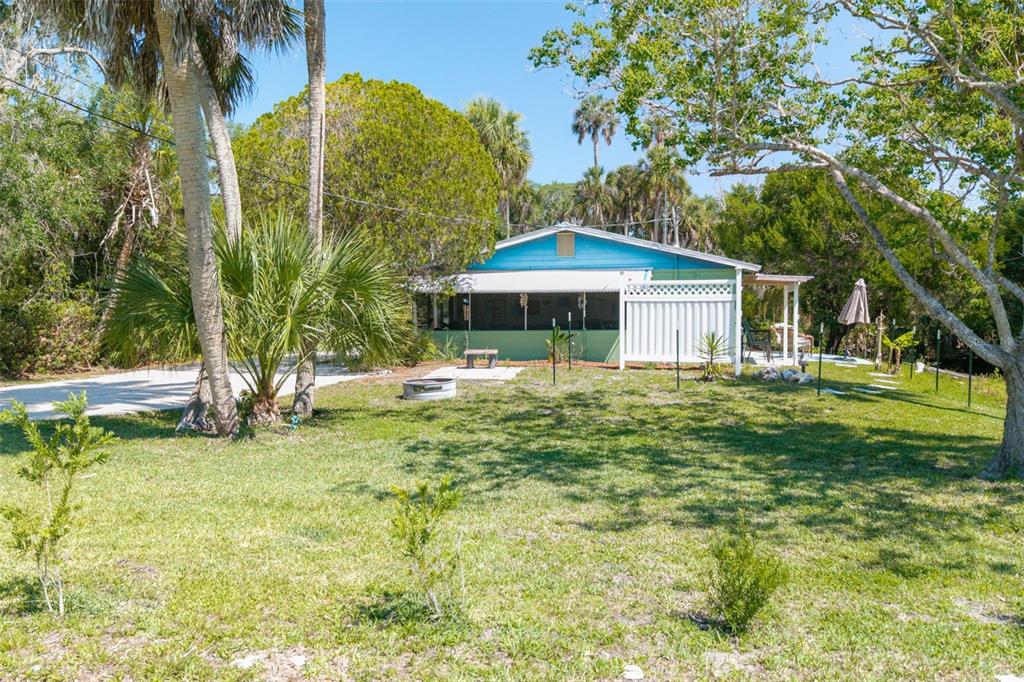 A blue house with a screened porch sits on a grassy lot with palm trees — 10709 W HALLS RIVER ROAD, HOMOSASSA, FL