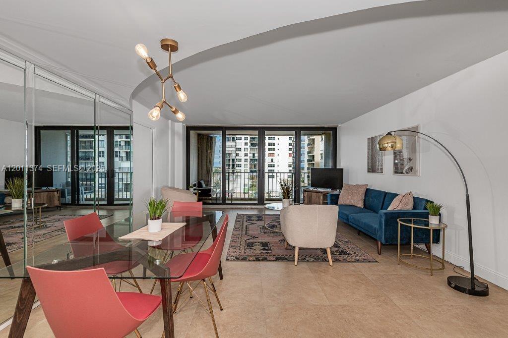 A living and dining area features a glass table, blue sofa, and floor-to-ceiling windows — 2401 S Ocean Dr # 604, Hollywood FL 33019, HOLLYWOOD, FL