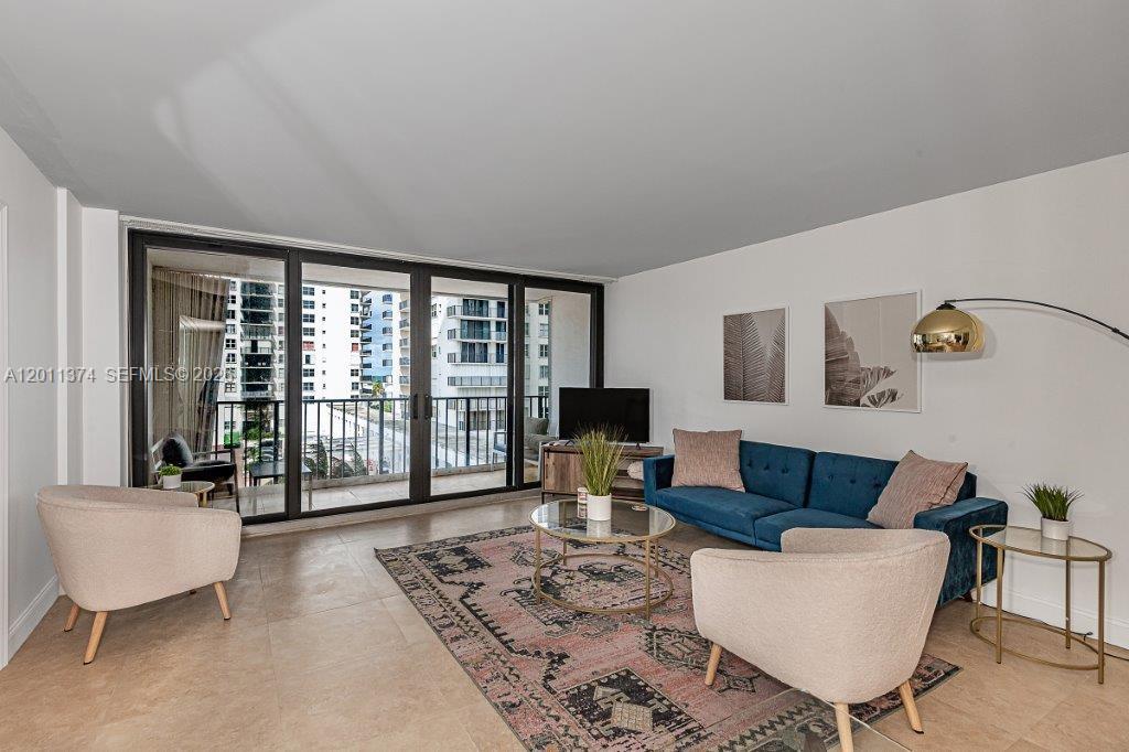 A living room features a blue sofa, two beige armchairs, and a balcony with city views — 2401 S Ocean Dr # 604, Hollywood FL 33019, HOLLYWOOD, FL