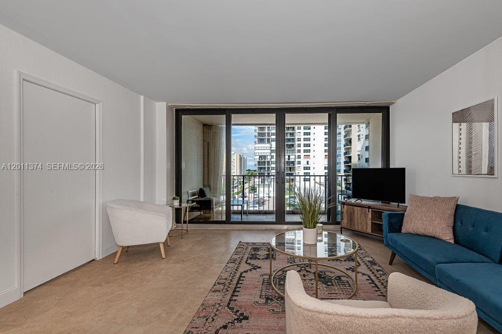 A living room features a blue sofa, two armchairs, a glass coffee table, and balcony access — 2401 S Ocean Dr # 604, Hollywood FL 33019, HOLLYWOOD, FL