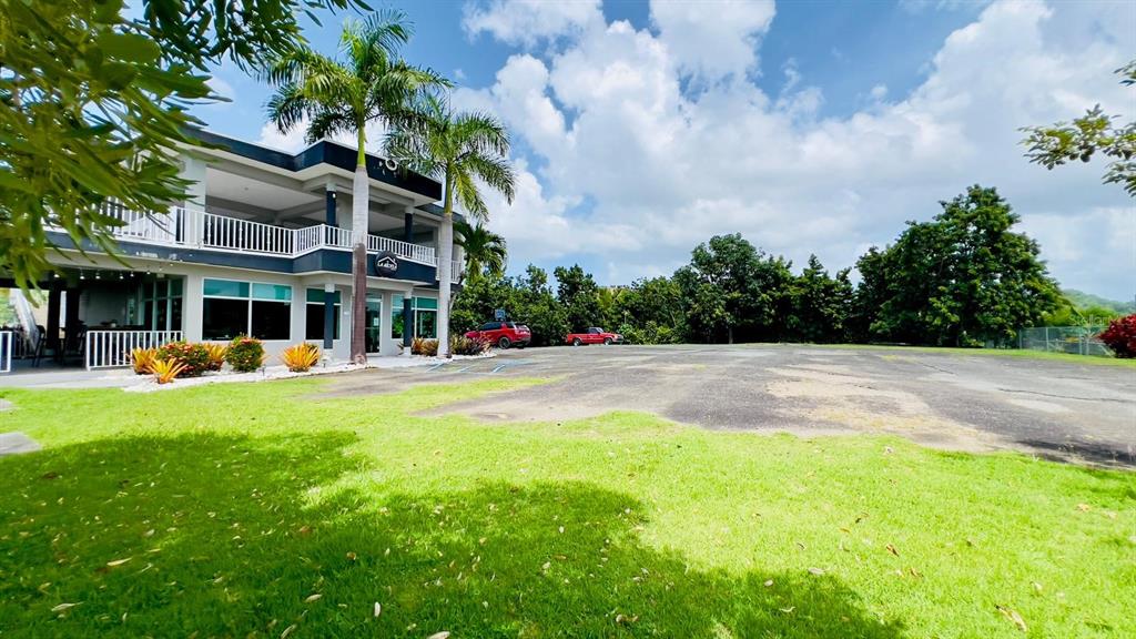 A two-story building with a parking lot and palm trees under a cloudy sky — Km 2.4 CARR 402, ANASCO, PR