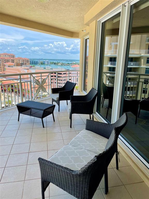 A balcony features wicker furniture and a view of the water and surrounding buildings — 10 PAPAYA STREET UNIT 1204, CLEARWATER, FL