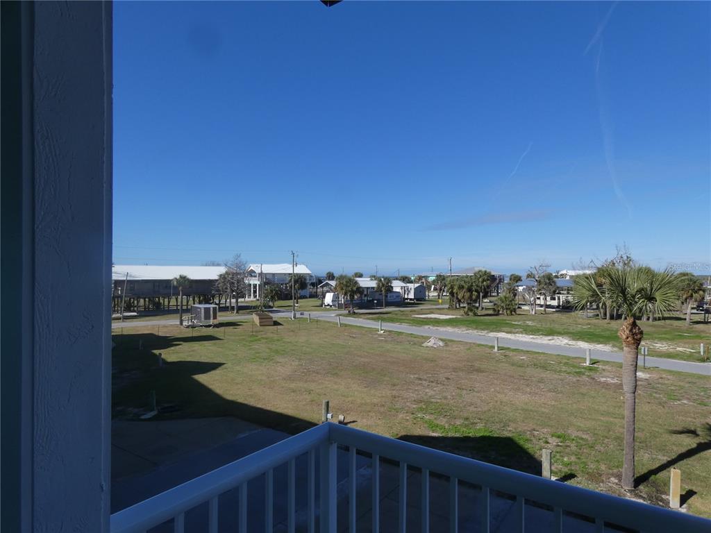 A view from a balcony overlooking a grassy lot, a road, and coastal houses — 502 MAIN STREET UNIT 106, HORSESHOE BEACH, FL