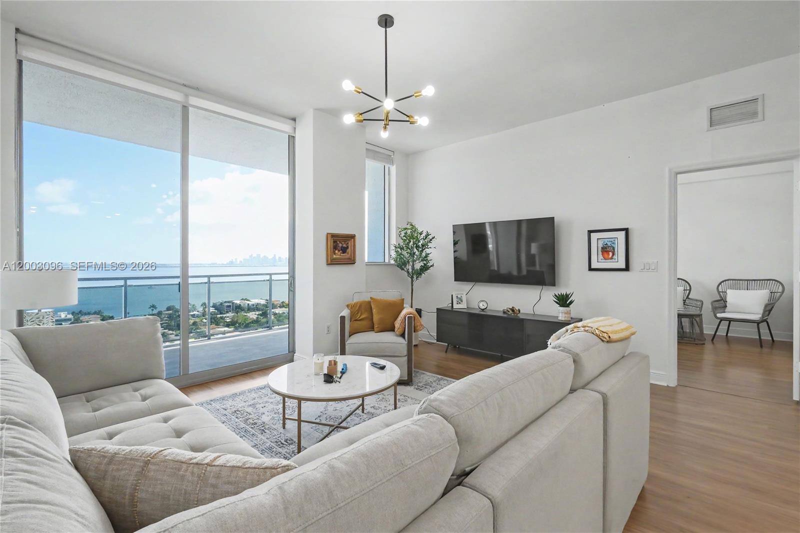 A living room features a sectional sofa, a marble coffee table, and a balcony view — 7901 Hispanola Ave # 1810, Miami FL 33141, MIAMI, FL