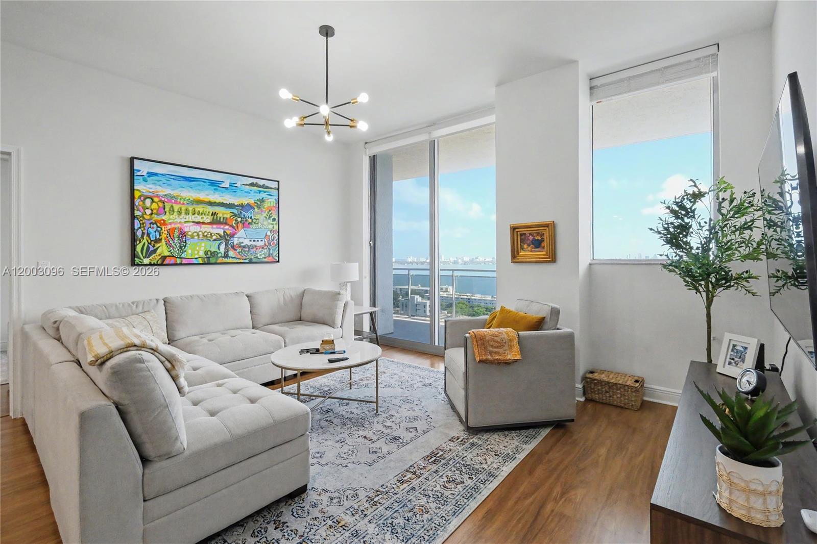 A living room features a sectional sofa, an armchair, a coffee table, and a balcony view — 7901 Hispanola Ave # 1810, Miami FL 33141, MIAMI, FL