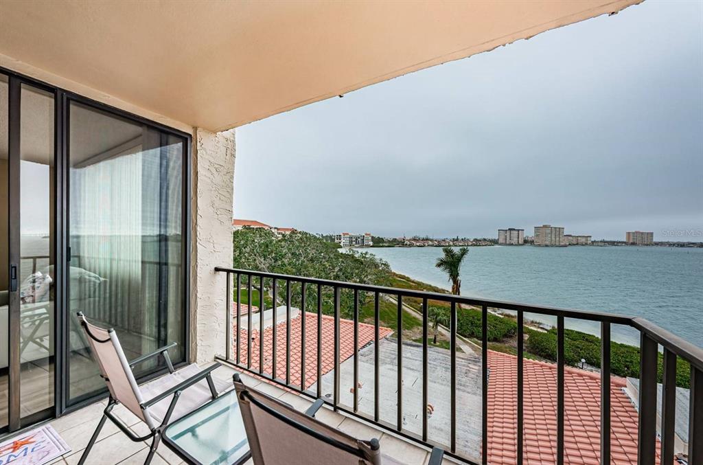 A balcony with chairs overlooks a body of water and distant buildings — 6218 PALMA DEL MAR BOULEVARD S UNIT 507, ST PETERSBURG, FL