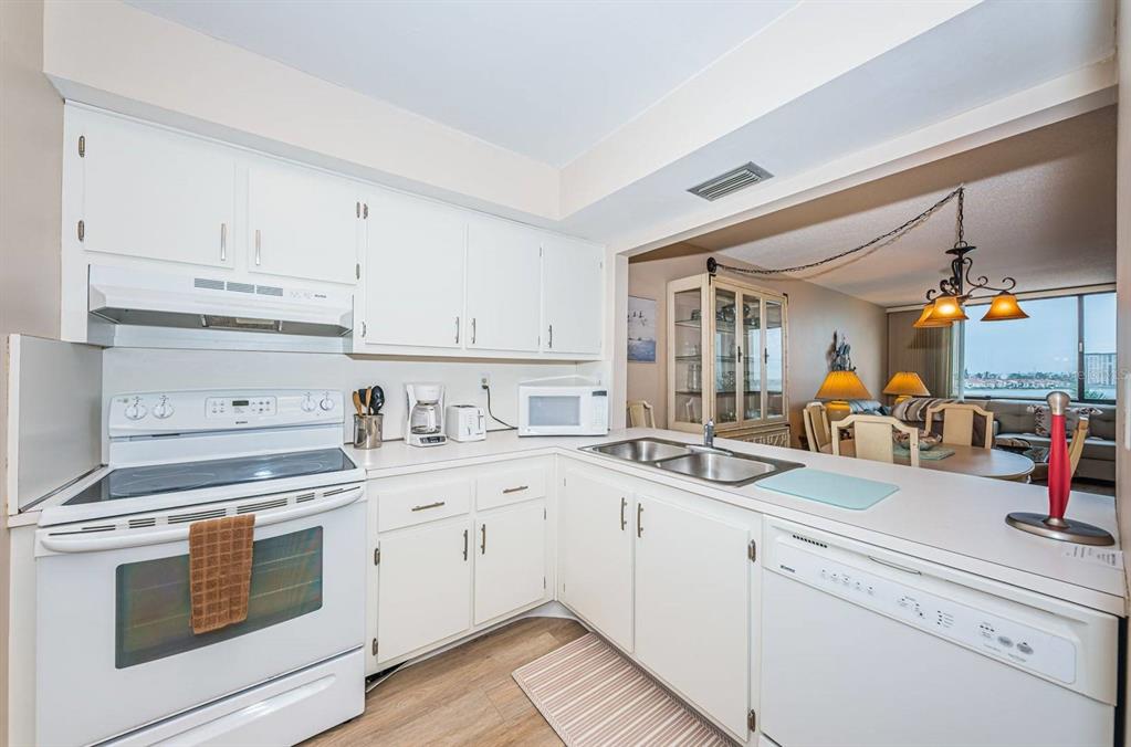 A kitchen with white cabinets, white appliances, and a view into the adjacent dining area — 6218 PALMA DEL MAR BOULEVARD S UNIT 507, ST PETERSBURG, FL