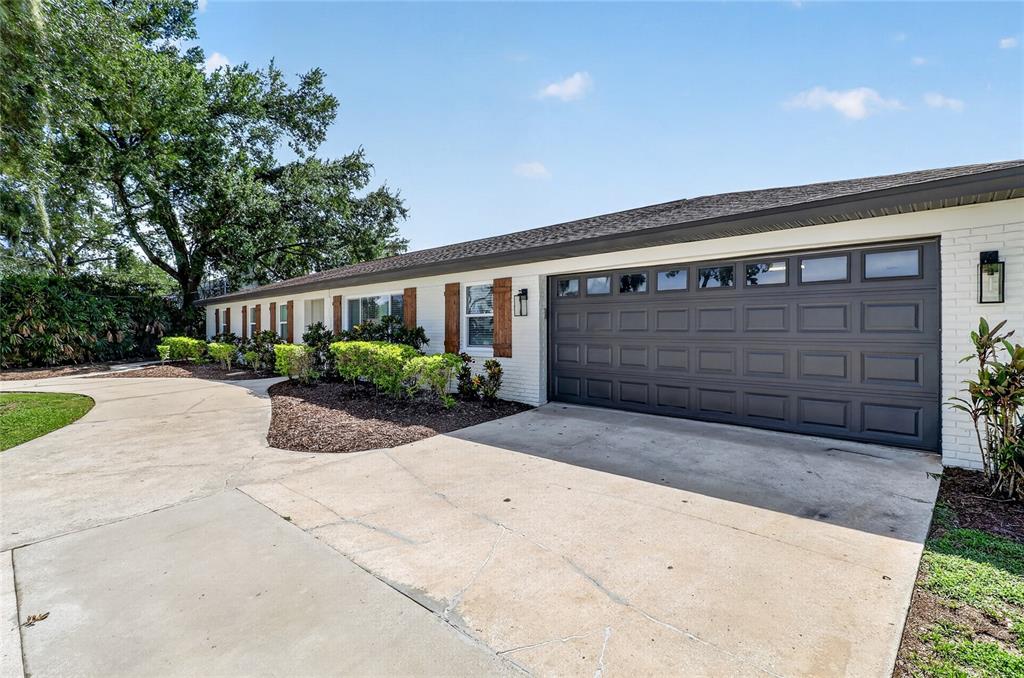 A white brick house exterior features a dark gray garage door and wooden window shutters — 706 S OAKWOOD AVENUE, BRANDON, FL