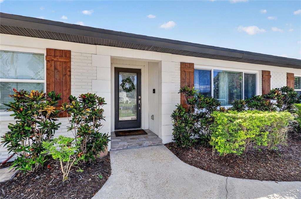 The exterior of a white brick house features a front door and landscaping — 706 S OAKWOOD AVENUE, BRANDON, FL