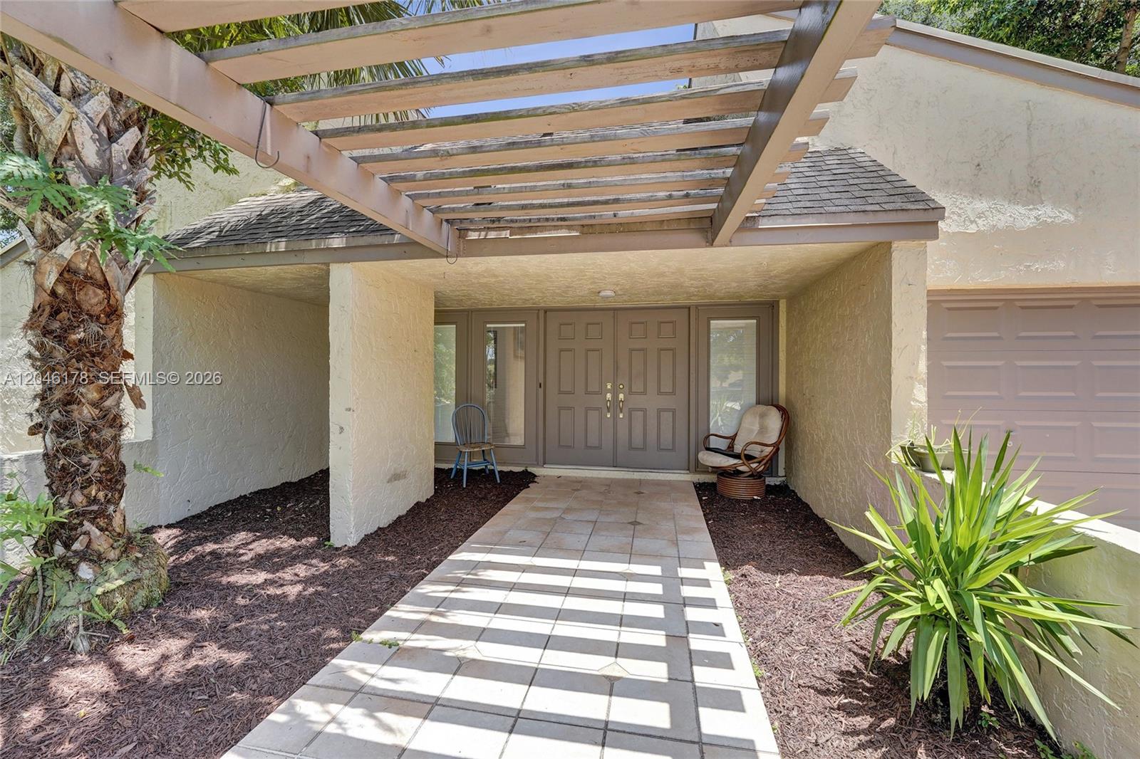 A tiled walkway leads to a double front door under a wooden pergola — 9120 SW 49th St, Cooper City FL 33328, COOPER CITY, FL