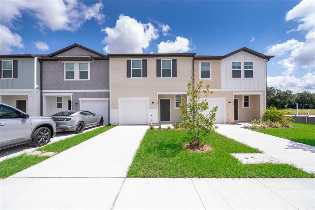 A row of three modern two-story townhomes with attached garages and concrete driveways — 3661 SPIRE DRIVE, DAVENPORT, FL