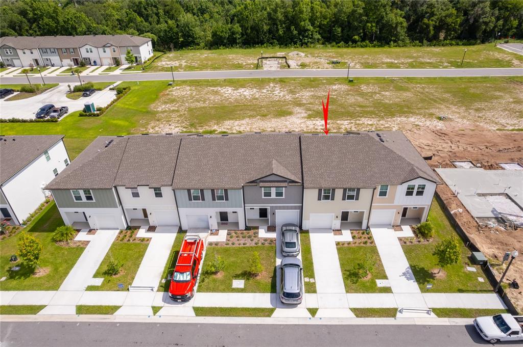 An aerial view shows a row of townhouses with driveways and a red arrow pointing to the roof — 3661 SPIRE DRIVE, DAVENPORT, FL
