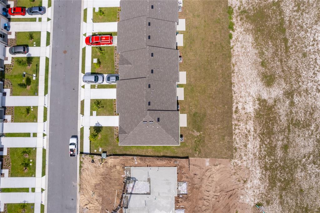 An aerial view shows a row of townhomes next to a construction site foundation — 3661 SPIRE DRIVE, DAVENPORT, FL