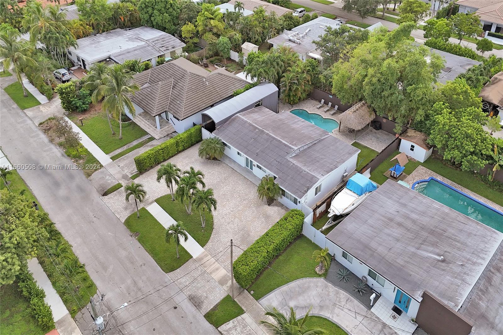 An aerial view shows several houses with swimming pools, paved driveways, and lush landscaping — 1910 N Hibiscus Dr, North Miami FL 33181, NORTH MIAMI, FL