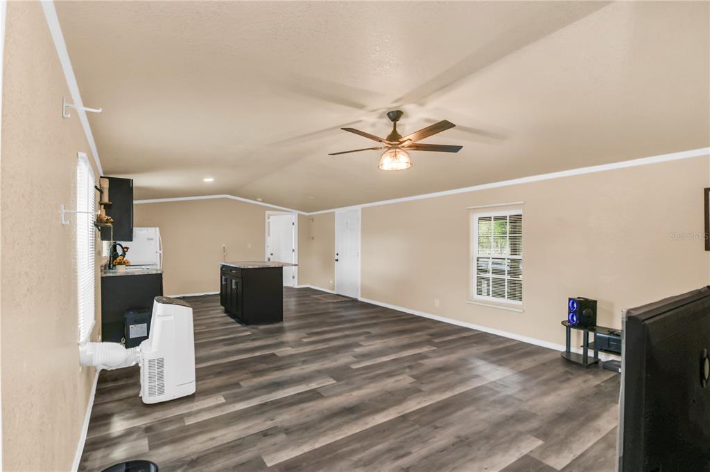 A living room with wood-look flooring, a ceiling fan, and an open kitchen area — 7457 NE HIGHWAY 349, OLD TOWN, FL