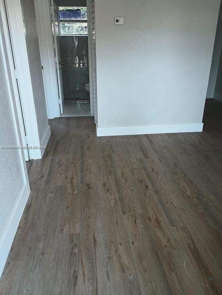 A view of a room with wood-look flooring leading to a bathroom doorway — 10540 SW 172nd St, Miami FL 33157, MIAMI, FL
