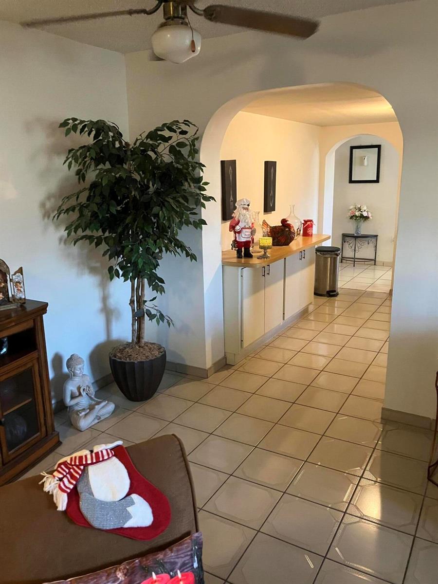 A tiled hallway leads through an arched doorway past a kitchen counter and a large plant — 7960 NW 174th Street, Hialeah FL 33015, HIALEAH, FL