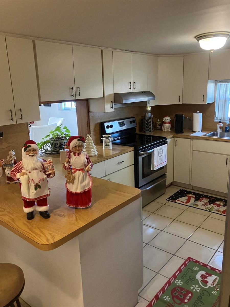 A kitchen features light-colored cabinets, a stainless steel stove, and holiday decorations on the counter — 7960 NW 174th Street, Hialeah FL 33015, HIALEAH, FL