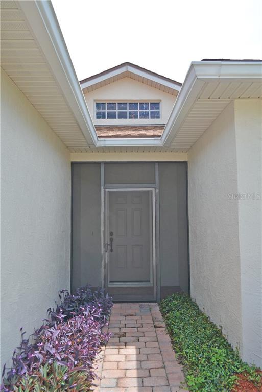 A paved walkway leads to a front door enclosed by a screen door and frame — 4314 BERWICK DRIVE, LAKE WALES, FL