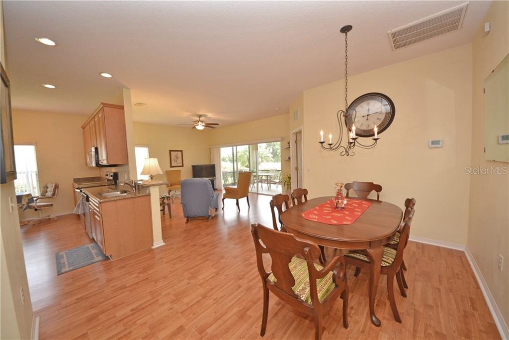 An open-concept dining area and kitchen feature wood-look flooring and a large wall clock — 4314 BERWICK DRIVE, LAKE WALES, FL