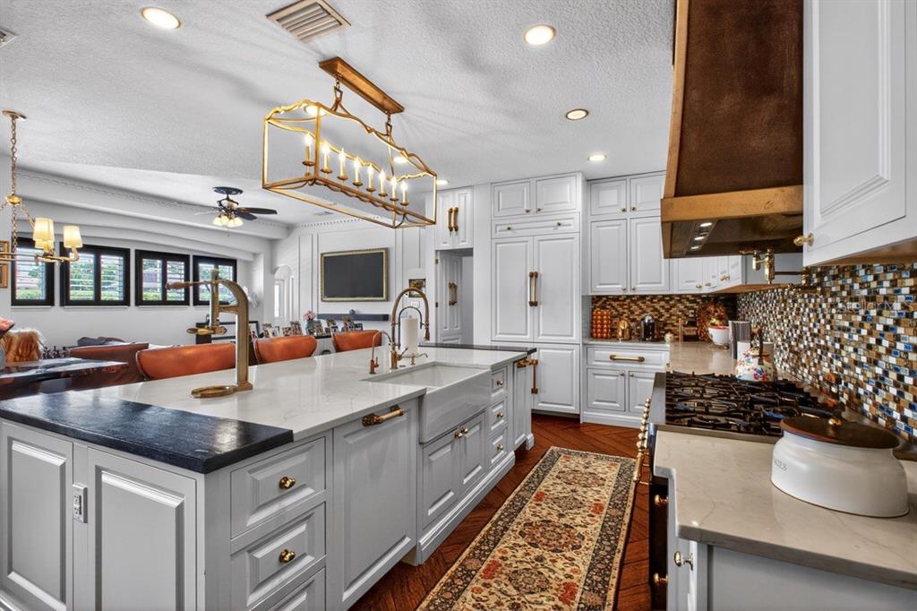 A kitchen features white cabinetry, a large island with a farmhouse sink, and a mosaic backsplash — 7707 HORSE FERRY ROAD, ORLANDO, FL