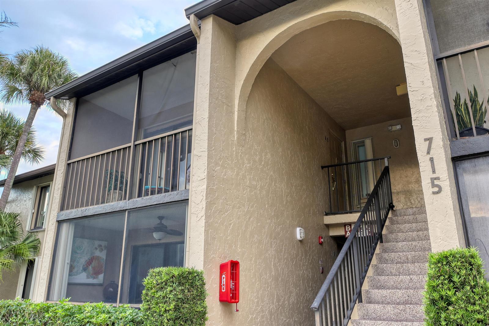 An exterior view of a two-story apartment building with a staircase and screened-in balconies — 715 Sunny Pine Way # A2, FL 33415, FL