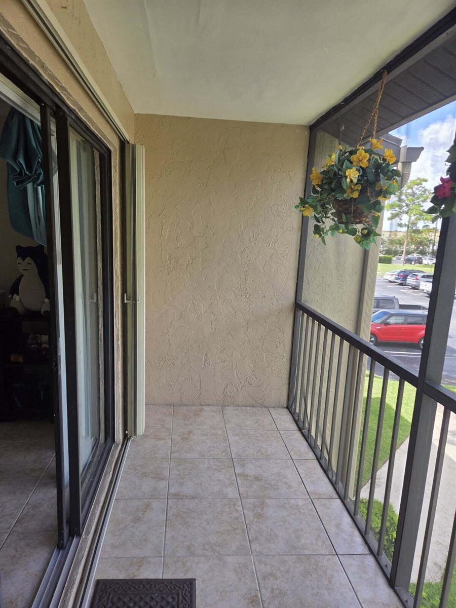 A tiled balcony with a screen enclosure overlooks a parking lot — 715 Sunny Pine Way # A2, FL 33415, FL