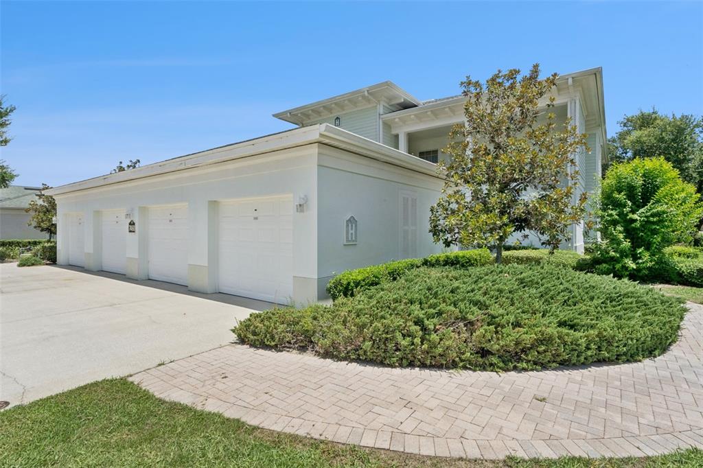 A covered balcony features white railings, wicker furniture, and a view of a neighborhood street — 7468 EXCITEMENT DRIVE UNIT 102, REUNION, FL