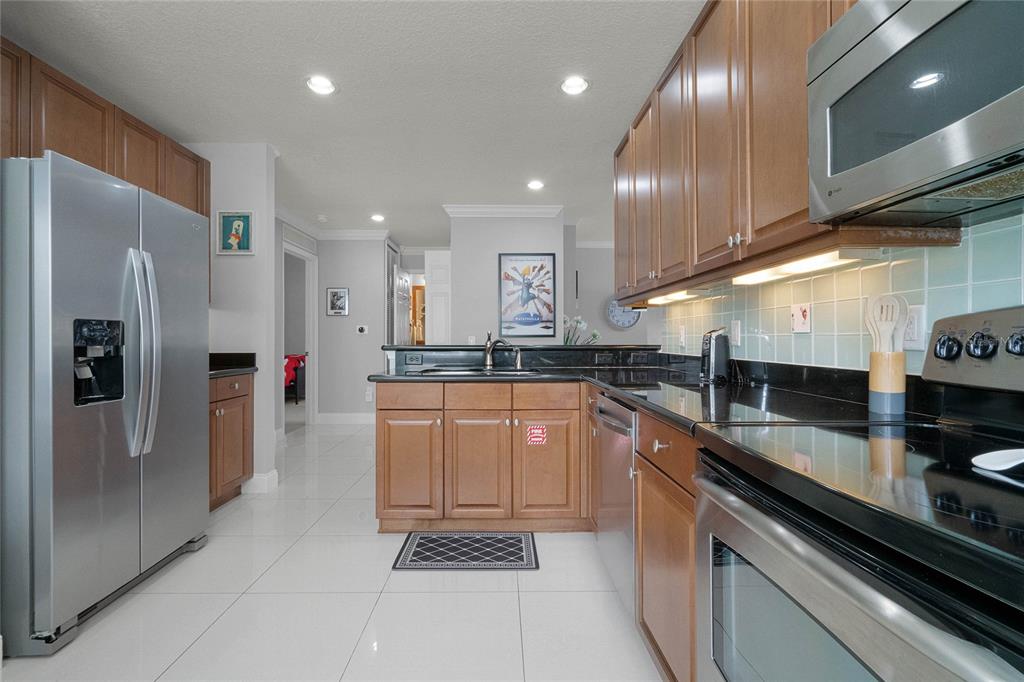 A multi-car garage exterior with a paved driveway and landscaped bushes under a blue sky — 7468 EXCITEMENT DRIVE UNIT 102, REUNION, FL