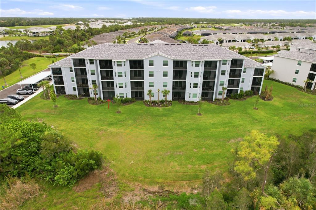An aerial view of a multi-story apartment building with a large lawn in front — 14191 HERITAGE LANDING BOULEVARD UNIT 1216, PUNTA GORDA, FL