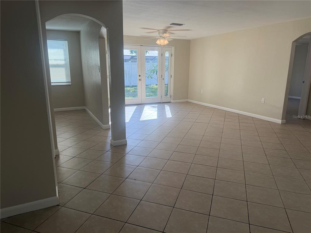 An open-concept living area features beige tile flooring, an arched entryway, and glass patio doors — 10141 OLD HICKORY LANE, PORT RICHEY, FL
