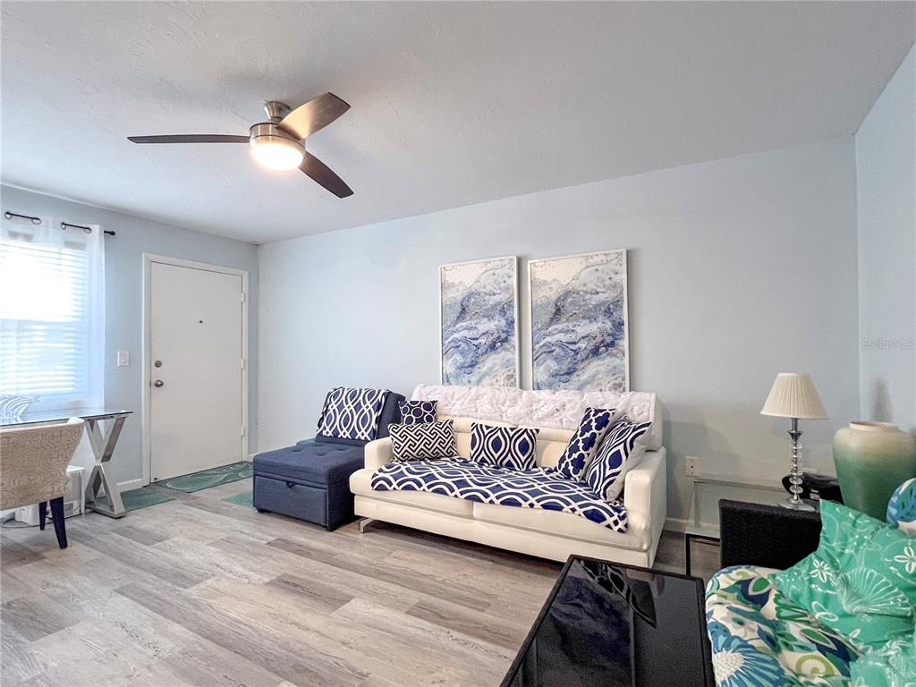 A living room features a white sofa with blue patterned pillows, wall art, and light flooring — 4480 IRONWOOD CIRCLE UNIT 112A, BRADENTON, FL