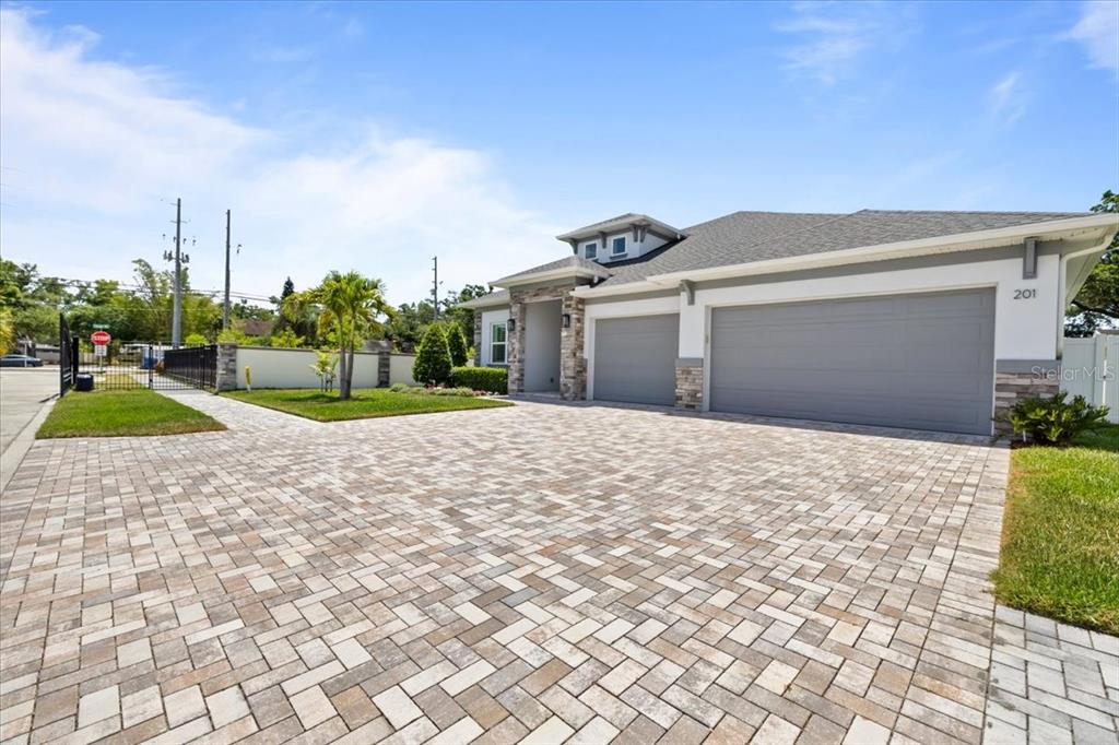A single-story house with a paved driveway, a three-car garage, and a stone-accented facade — 201 LAROCCA COURT, PALM HARBOR, FL