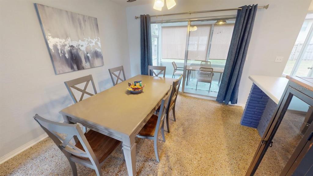 A dining room features a gray table, matching chairs, terrazzo flooring, and sliding glass doors — 328 SLAYTON AVENUE, SOUTH DAYTONA, FL