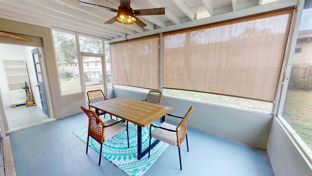 A screened-in porch features a dining table, four chairs, a patterned rug, and ceiling fan — 328 SLAYTON AVENUE, SOUTH DAYTONA, FL