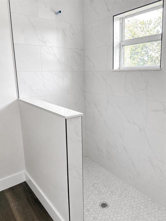 A walk-in shower features white marble-look wall tiles, a hexagonal tile floor, and a half wall — 14973 NW 304TH STREET, OKEECHOBEE, FL