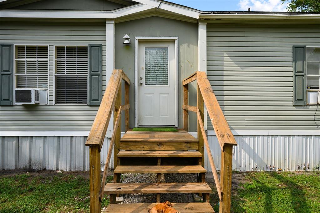 A wooden staircase leads to the front door of a light green mobile home — 9798 STATE ROAD 100 W, STARKE, FL