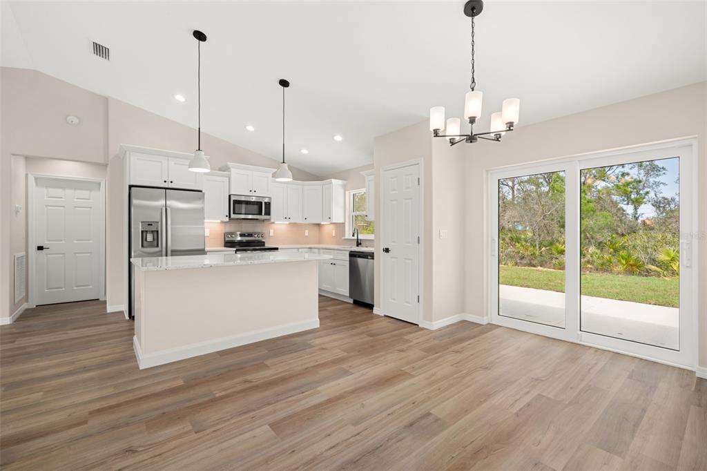 A kitchen with white cabinets, stainless steel appliances, and a dining area with sliding doors — 4206 JAGUAR DRIVE, SEBRING, FL