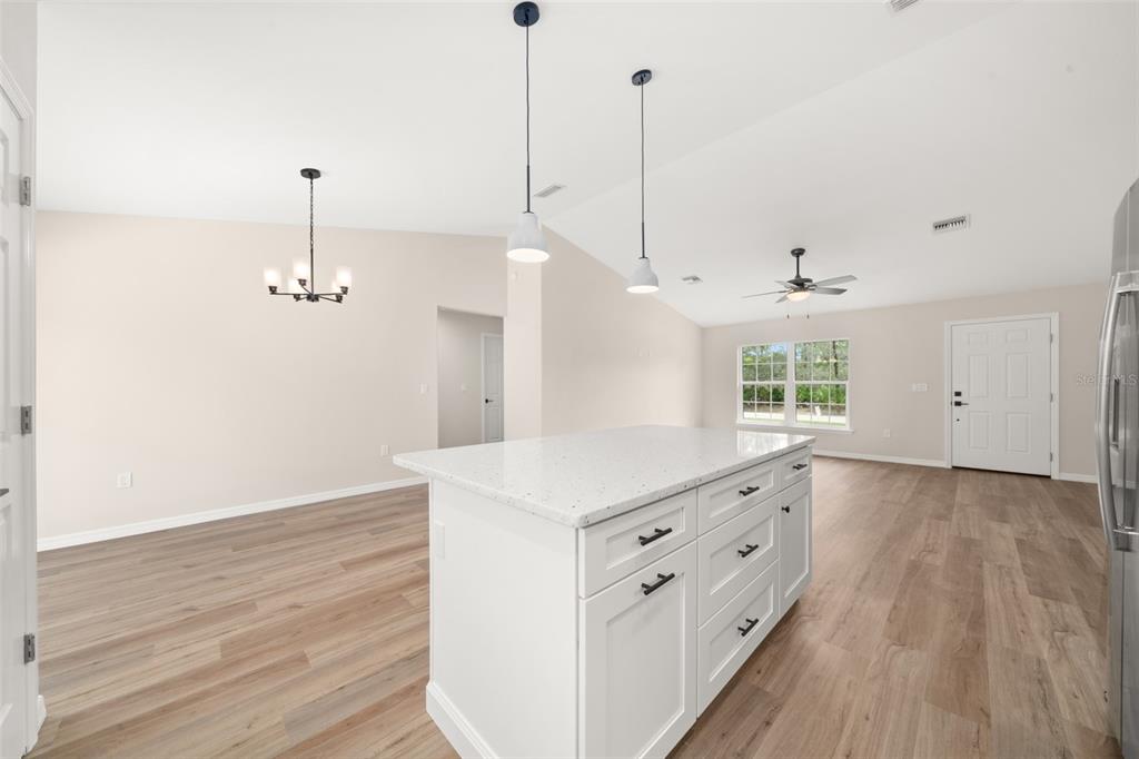 A kitchen island with white cabinets and a speckled countertop sits in an open-concept room — 4206 JAGUAR DRIVE, SEBRING, FL