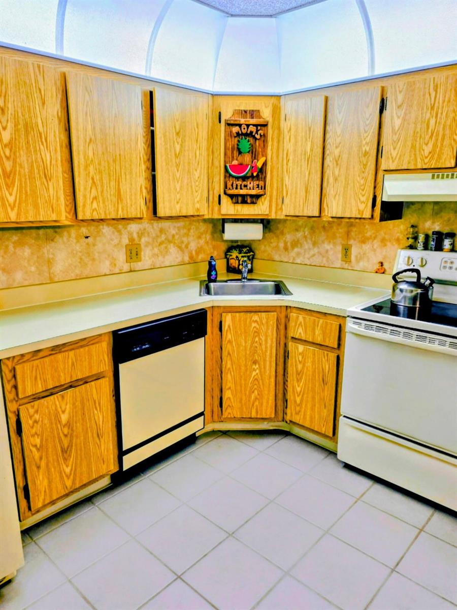 A kitchen with light wood cabinets, a corner sink, and white appliances — 423 Pine Glen Lane # 1, FL 33463, FL