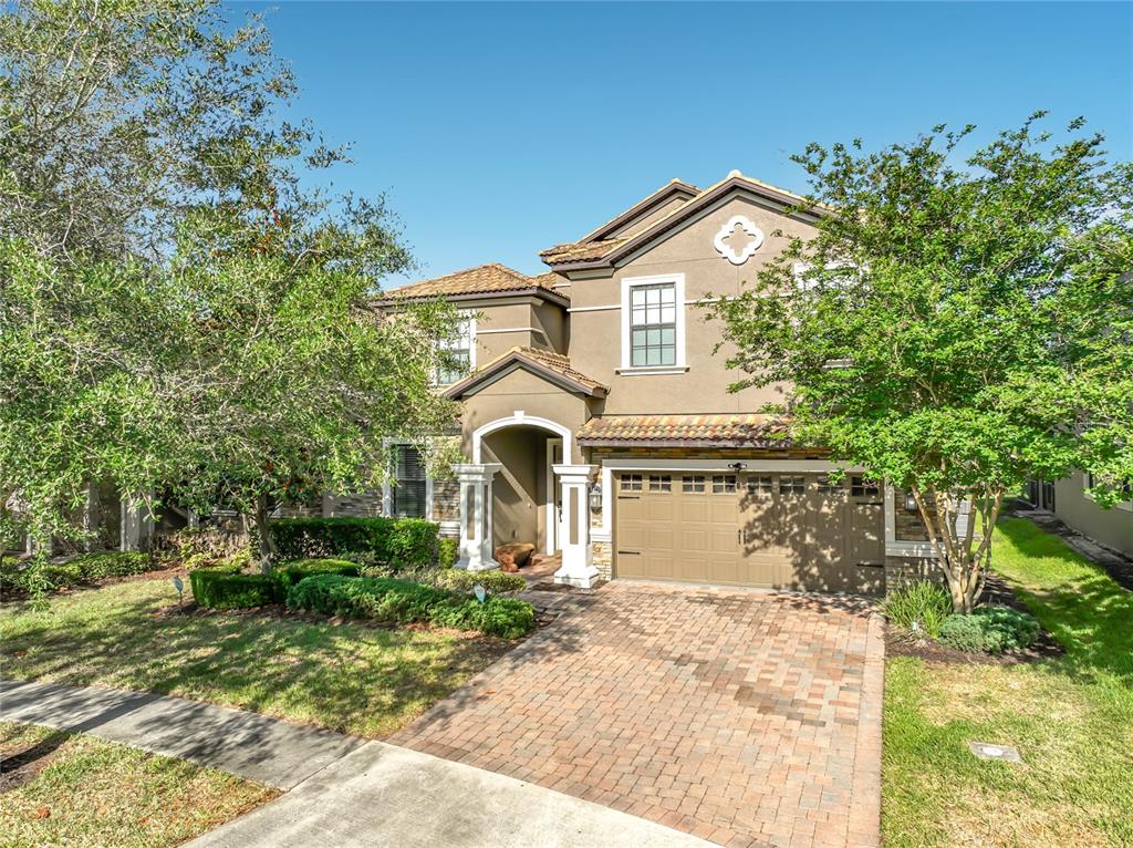 A two-story house with a tan stucco exterior, a brick paver driveway, and a garage — 1505 ROLLING FAIRWAY DRIVE, DAVENPORT, FL